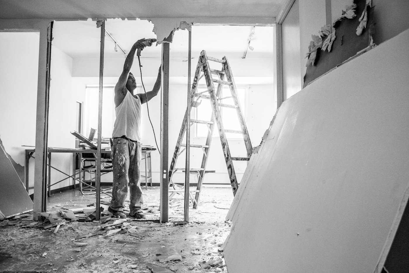 Worker on a ladder hanging drywall